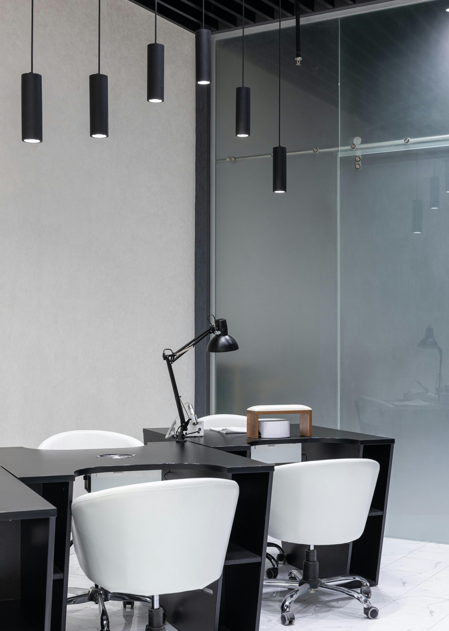 A sleek modern office interior featuring elegant black furniture and pendant lights.